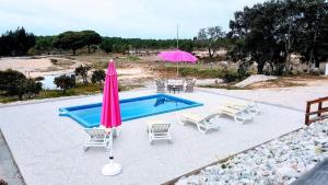 een zwembad met stoelen en een roze parasol en een tafel en stoelen bij Quinta da Sonia, Melides in Melides