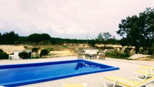 een zwembad met 2 stoelen en een tafel bij Quinta da Sonia, Melides in Melides