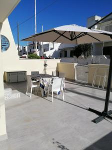 a patio with a table and chairs and an umbrella at Villetta Lido Marini in Lido Marini