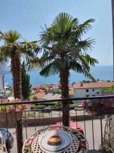 a table on a balcony with palm trees and the ocean at Alba Opatija in Opatija