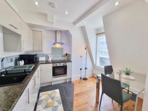 a kitchen with white cabinets and a glass table at Lovely 1 Bed Apartment in Old Market Square in Nottingham