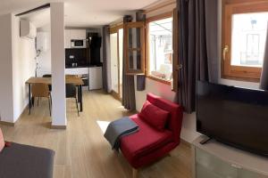 ein Wohnzimmer mit einem roten Stuhl und einem TV in der Unterkunft Casa Ferrers piso 5. Precioso ático con terraza in Tarragona