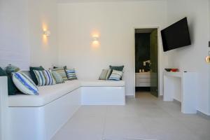 a white living room with a white couch with pillows at Levanta guesthouse in Schinoussa