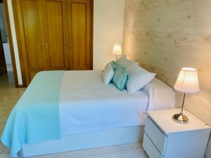 1 dormitorio con cama blanca y almohadas azules en Apartamento en Samil, en Vigo