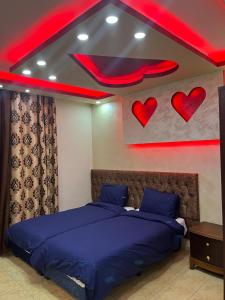a bedroom with a bed with blue sheets and hearts on the wall at Shihan hotel suites in Amman