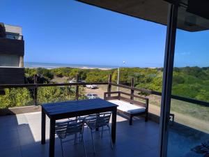 a table and chairs on a balcony with a view of the ocean at Linda Bay 202 in Mar de las Pampas