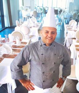 a man in a chefs hat standing in a restaurant at Hotel Raya Tichy in Tichi