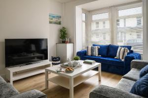 a living room with a blue couch and a tv at Fenton House - Modern, 4 Bedroom, Pets Accepted in Porthcawl