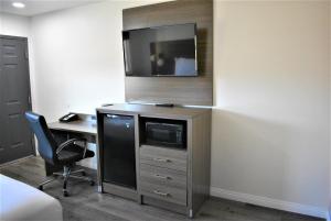 a room with a desk and a tv on a wall at Signature Anaheim Maingate in Anaheim
