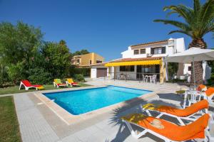 een zwembad met stoelen en een parasol en een huis bij Villa Tupi by Villa Plus in Boliqueime