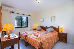 een slaapkamer met twee bedden en een tafel met een lamp bij Villa Tupi by Villa Plus in Boliqueime +15 foto's