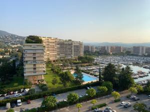 eine Luftansicht eines großen Apartmentgebäudes mit einem Parkplatz in der Unterkunft Cannes Marina Résidence Le Surcouf - Studio de 28m2 au 10ème étage avec piscine, terrasse, parking, vue montagne et port : Mandelieu-La Napoule in Mandelieu-la-Napoule