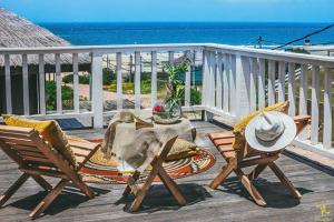 a deck with two chairs and a table and a hat at Desiderata in Punta Del Diablo
