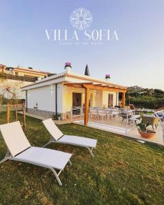a house with two lounge chairs in the yard at Villa Sofia *Luxury experience in Calabria in Zambrone