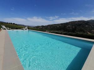 a large blue swimming pool with two white chairs at 44House - Quinta do Casal in Mesão Frio