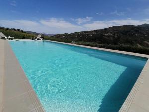 a large blue swimming pool with two chairs in it at 44House - Quinta do Casal in Mesão Frio