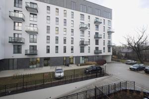 a white building with cars parked in a parking lot at Targowa 10 Modern 2BR Apt in Warsaw