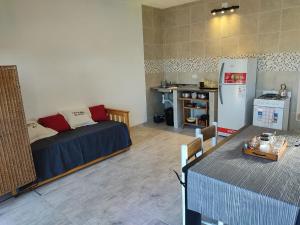 a living room with a bed and a table and a refrigerator at Villa Aurora in Potrero de Garay