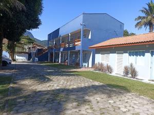 un bâtiment blanc avec un palmier en face dans l'établissement Maresias Flat's Unidade II, à Maresias