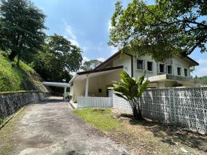 a white house with a fence next to a dirt road at Bukit Tunku KLCC Grande Villa 11 by Vale Pine in Kuala Lumpur