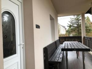 un porche con un banco de madera y una puerta en Veranda Apartman, en Nyíregyháza