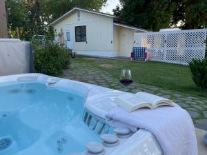 a hot tub with a glass of wine and a book at Luxury Riverside Estate - 3BR Home or 1BR Cottage or BOTH - Sleeps 14 - Swim, fish, relax, refresh in Anderson