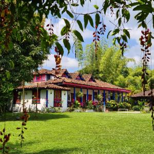 une maison avec une pelouse verte devant elle dans l'établissement El Percal Hacienda Hotel, à Montenegro