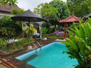 a swimming pool with an umbrella next to a house at Pantai Bungalow Lembongan Island in Nusa Lembongan