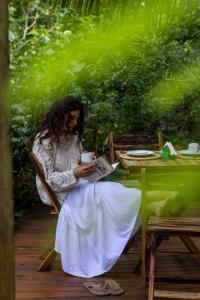 a woman sitting at a table with a cup of coffee at Beco do Pescador in Caraíva