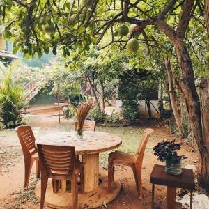 a wooden table and chairs under a tree at Jaana Guest in Sigiriya