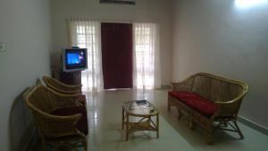 a living room with two chairs and a tv at Indeevaram Apartments in Kovalam