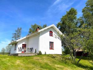 Casa blanca con ventanas rojas en un campo de hierba en Holiday home HOVA IV, en Hova