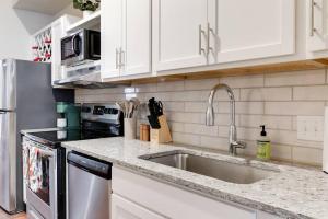 a kitchen with white cabinets and a stainless steel sink at Cozy Chic Retreat in the Heart of RVA in Richmond