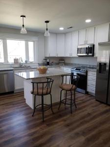 a kitchen with white cabinets and a island with two bar stools at Red River Gorge Creekside, New*Spacious *2 baths! in Stanton +10 photos