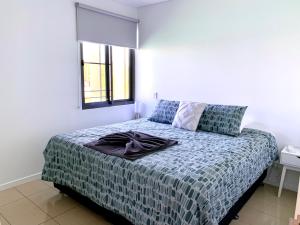 a bedroom with a bed with a blanket and a window at Serenity Harbour Views at Darwin Waterfront in Darwin