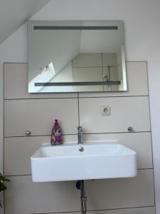 a white bathroom sink with a mirror above it at Deich Quartier 9.2 in Dorum-Neufeld