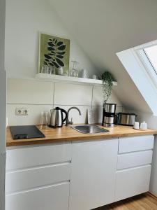 a kitchen with white cabinets and a wooden counter top at Deich Quartier 9.2 in Dorum-Neufeld