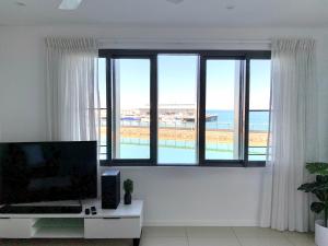 a living room with a large window with a view of the beach at Serenity Harbour Views at Darwin Waterfront in Darwin