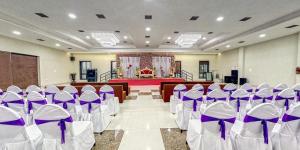 a banquet hall with purple and white chairs and a stage at The Aanandam Hotel Resort in Itārsi +45 photos