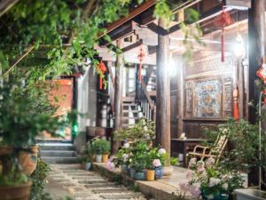 un couloir avec des plantes en pot et des escaliers dans un bâtiment dans l'établissement Tuo Tuo Guest House, à Lijiang