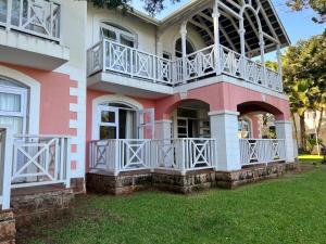 a pink and white house with a balcony at Caribbean Estates 29 Montego Bay in Port Edward
