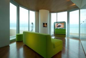 a green couch in a living room with windows at i-Suite Hotel in Rimini