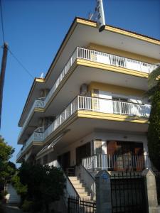 a white building with balconies and a fence at Iris Hotel in Nea Kalikratia