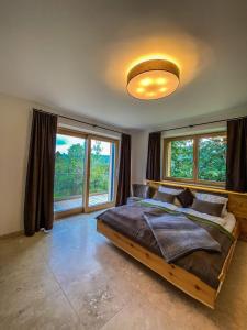 ein Schlafzimmer mit einem großen Bett in einem Zimmer mit Fenstern in der Unterkunft Ferienvilla Joachimsberg mit Swimspa und Sauna in Wienerbruck