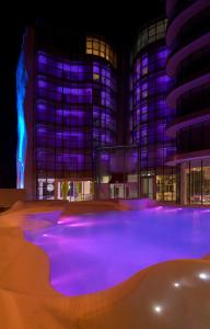 a building with purple lights in front of a pool at i-Suite Hotel in Rimini