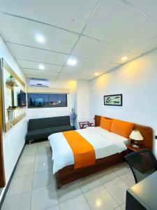 1 dormitorio con 1 cama grande con almohadas de color naranja en Hotel Madrigal, en Portoviejo