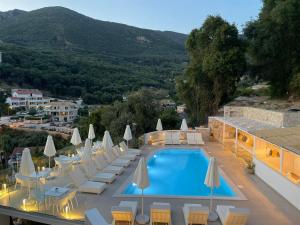 a hotel with a pool and chairs and a mountain at Gallery Suites Parga in Parga