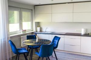 - une cuisine avec une table et des chaises bleues dans l'établissement Studijos tipo apartamentai Tauragėje, à Tauragė