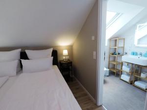 1 dormitorio con 1 cama blanca grande y lavamanos en -Neubau- 30qm Dach-Apartment en Fulda