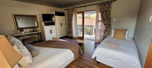 a bedroom with two beds and a television and a balcony at Solo Gracia Guesthouse in Bloemfontein